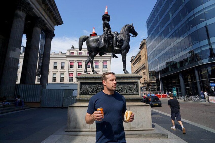 Un uomo mangia un hot dog di fronte a una statua di un cavaliere. 5