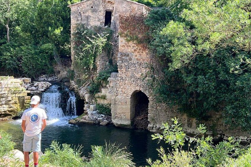 A stone building with a waterfall, surrounded by greenery. 1