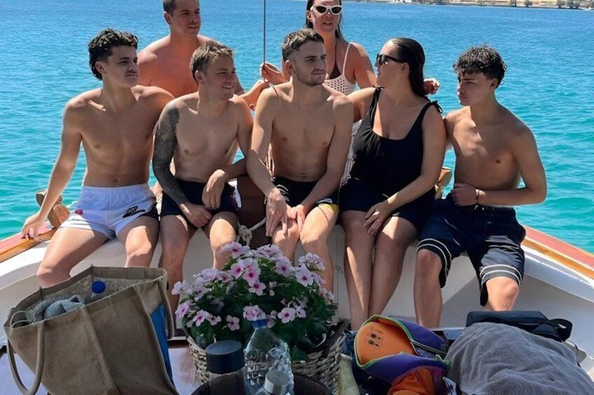 Un grupo de personas en un bote frente a un mar azul cristalino. 4