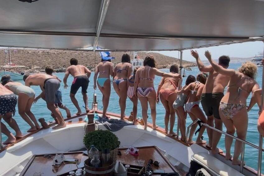 Un grupo de personas en un bote, algunas con trajes de baño, a punto de bajarse al agua. 3