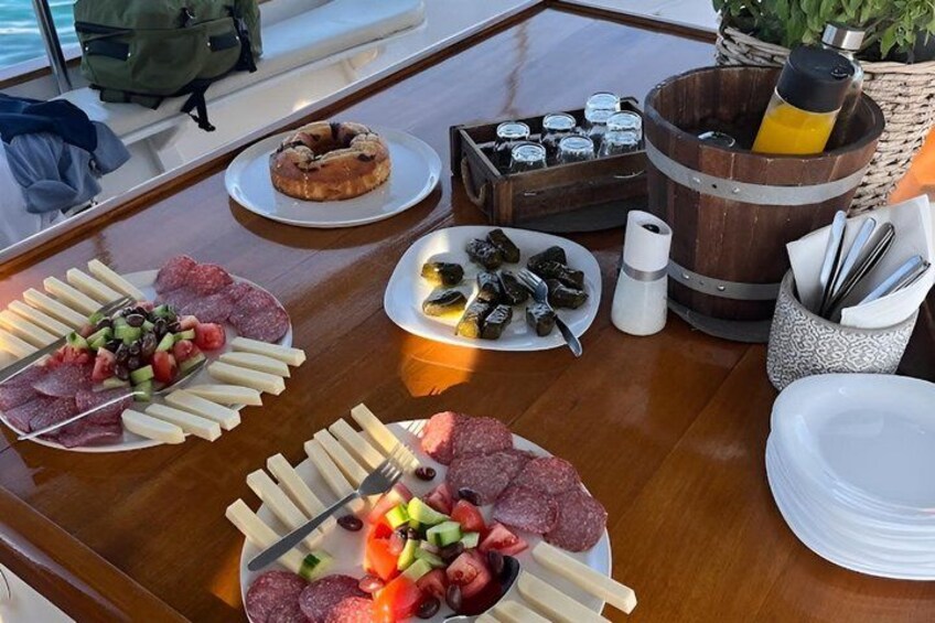 Una mesa de madera con diversas opciones de comida, incluyendo tablas de embutidos, una cesta de salsas y una botella de jugo. 2