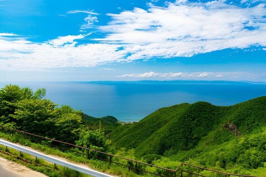 Un paysage côtier caractérisé par de luxuriantes collines verdoyantes, un ciel bleu azur et une mer calme. 2