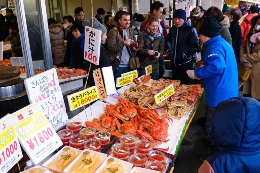 Un marché aux poissons et fruits de mer où une variété de produits sont exposés sur des étals, et des panneaux indiquent les prix. 1
