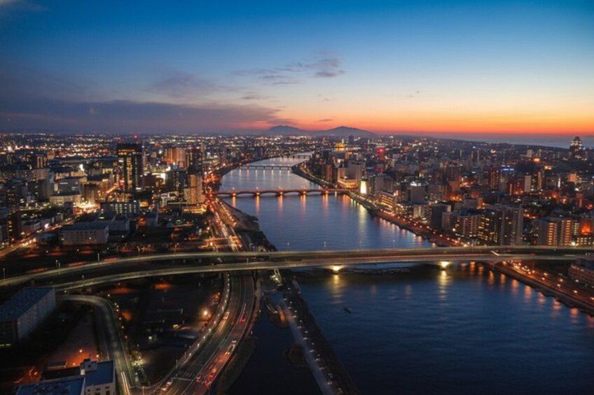 Une vue d’une ville au crépuscule, avec une rivière, des ponts et des bâtiments illuminés. 5