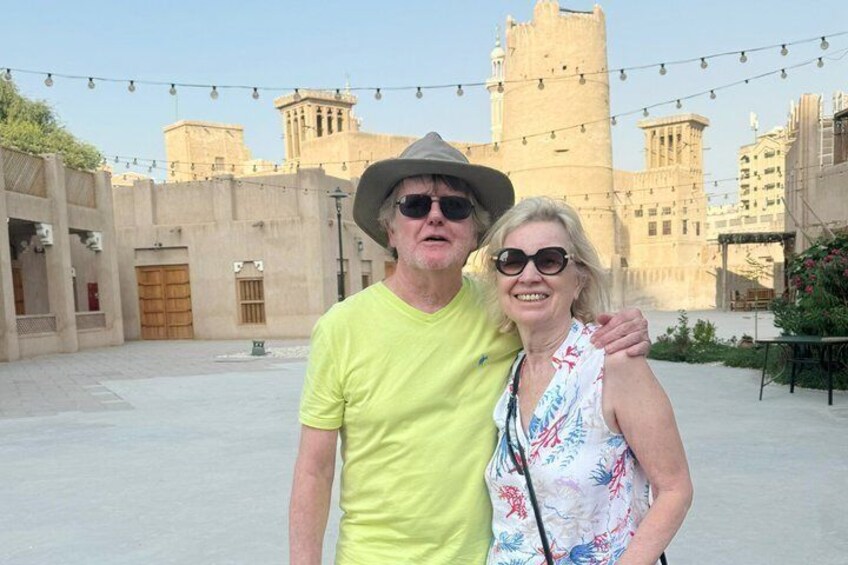 A man and woman standing in an outdoor courtyard with a historic building in the background. 5
