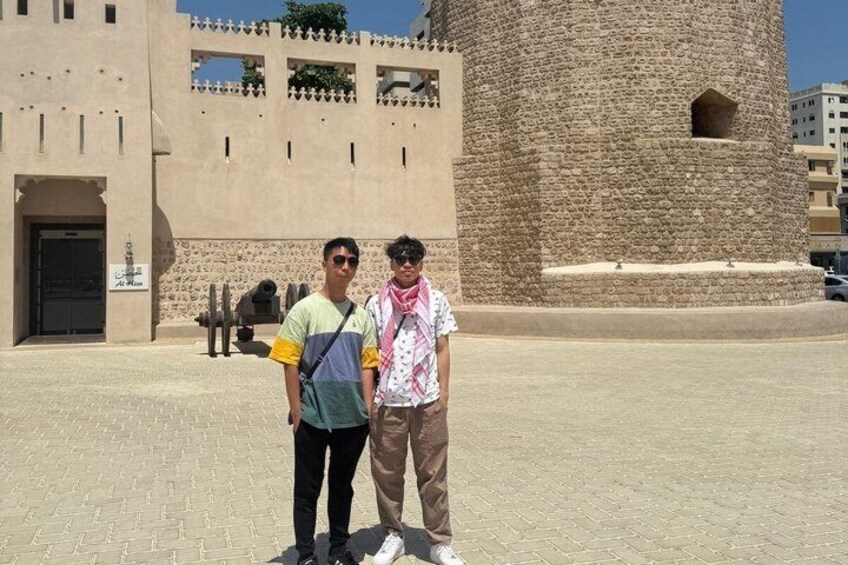 Two people standing in front of a historic building with a large stone tower. 4