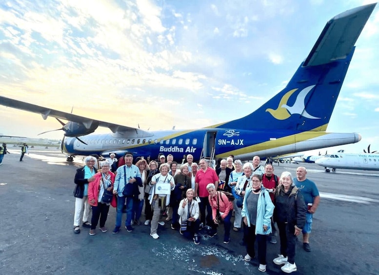 A group of people posing in front of a Buddha Air aircraft with the registration number 9N-AJX. 5