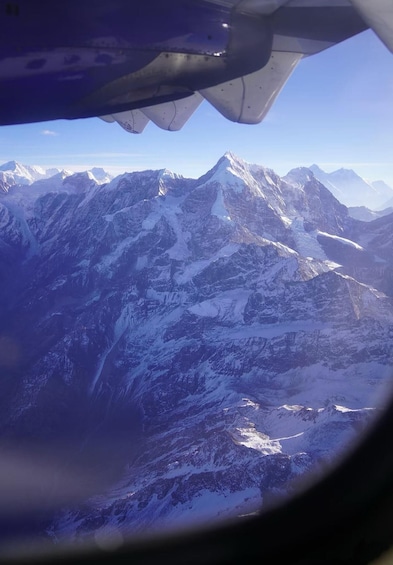 A snow-covered mountain range viewed from an airplane window. 3