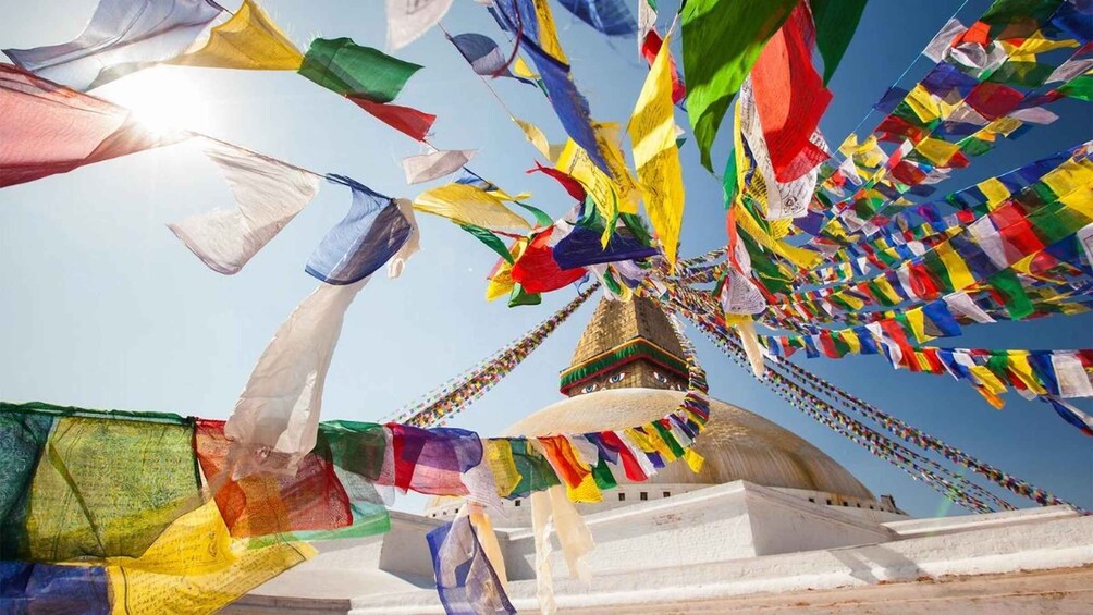 A colorful prayer flag arrangement in front of a domed building. 2