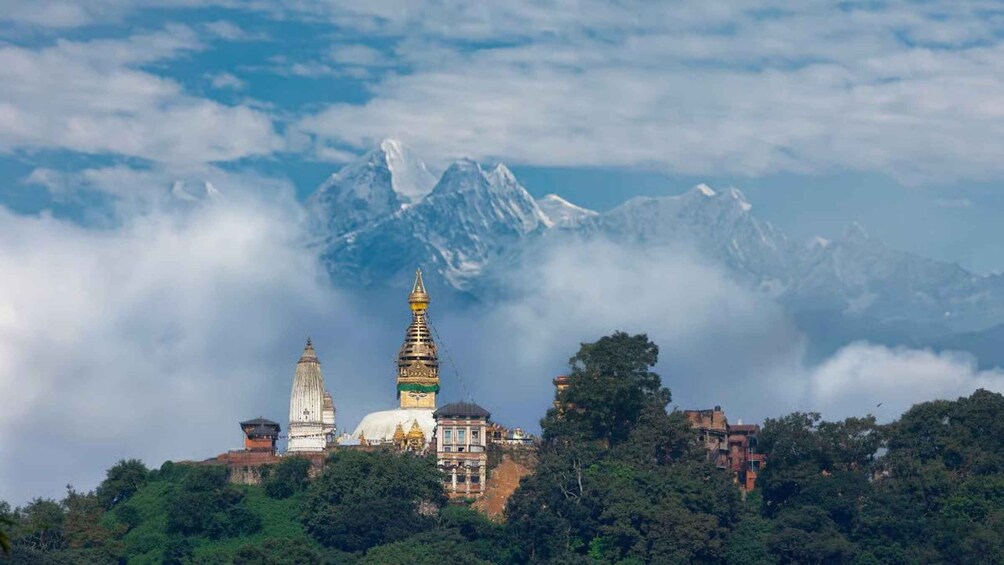 A mountainous landscape with a temple complex in the foreground and snow-capped peaks in the background. 4