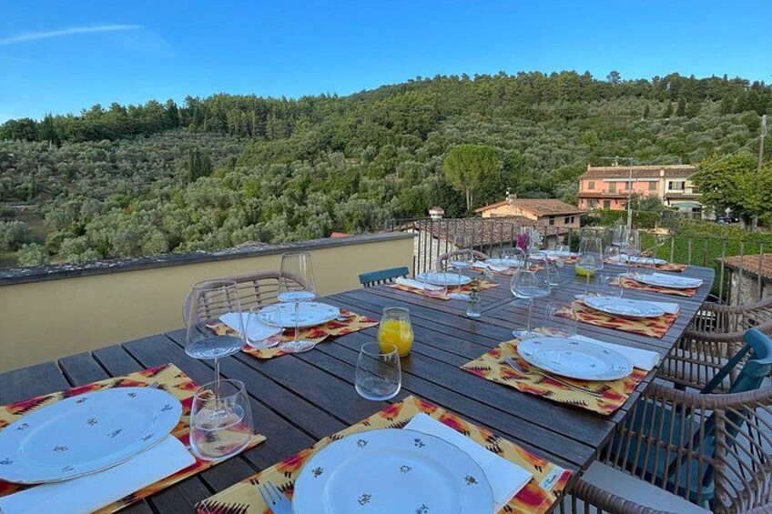 A table set for dining with a scenic view of a forested hill and buildings in the background. 3