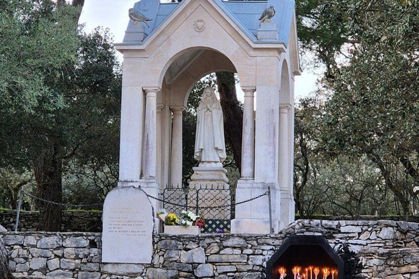 A stone monument with an arched structure, a statue, and a plaque. 5