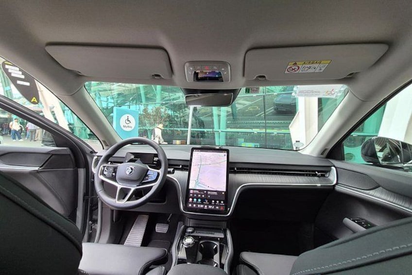 A car interior with a steering wheel, dashboard, and center console. 3