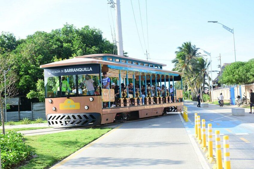 A tram with passengers, a sidewalk, and yellow bollards. 3