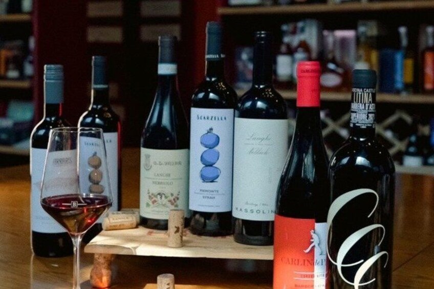 A variety of wine bottles and glasses on a wooden table. 2