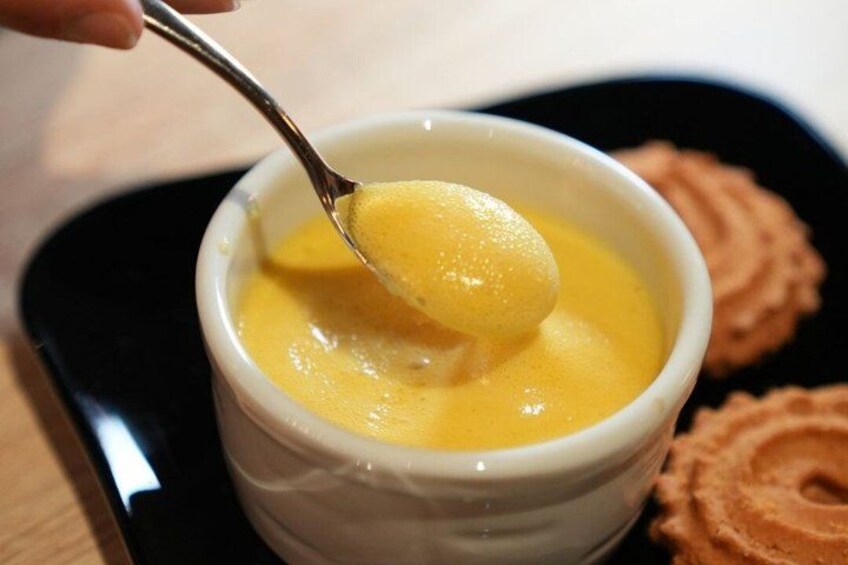 A white bowl with a yellow dessert being scooped with a spoon. 4