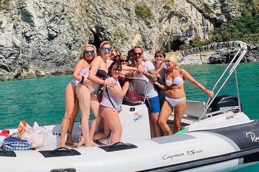 A group of people on a boat with rocky cliffs in the background. 4