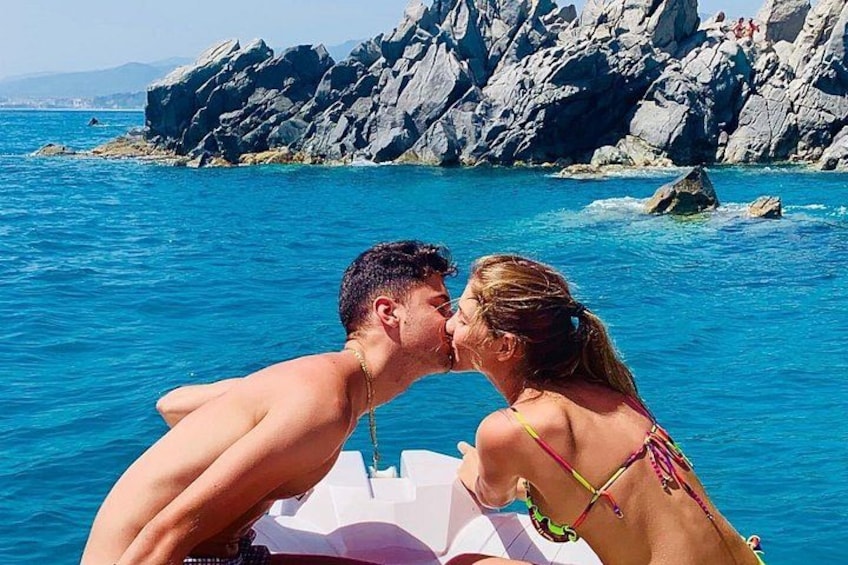 A couple kissing on a boat with rocky cliffs in the background. 3