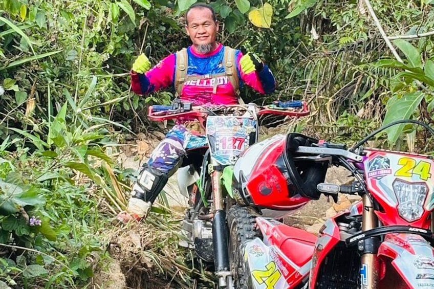 En person på en dirtbike med nummer 24 foran, omgivet af tæt grøn vegetation. 5