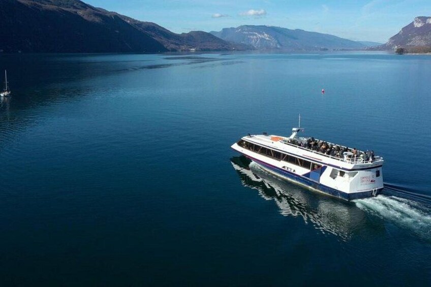 A large white boat with blue accents on calm water, surrounded by mountains. 5