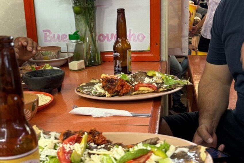 Una mesa de comedor con platos de comida, una botella y un florero. 2