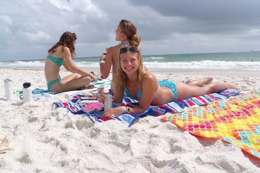 Tre persone su una spiaggia con un asciugamano colorato e una bottiglia d'acqua. 1