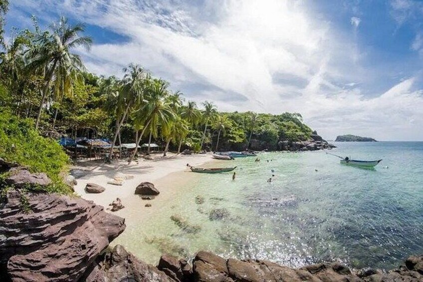 Una spiaggia tropicale con acque limpide, palme e barche. 5