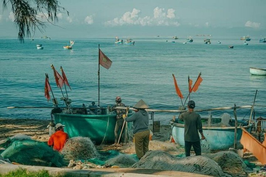 Una spiaggia con barche da pesca, persone e bandiere. 2