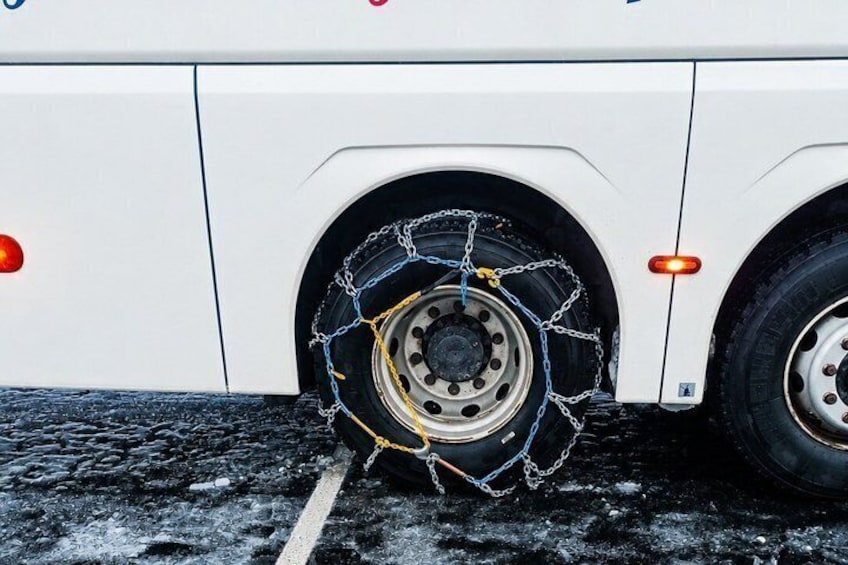 Un autobus blanc dont une des roues est protégée par un filet. 4