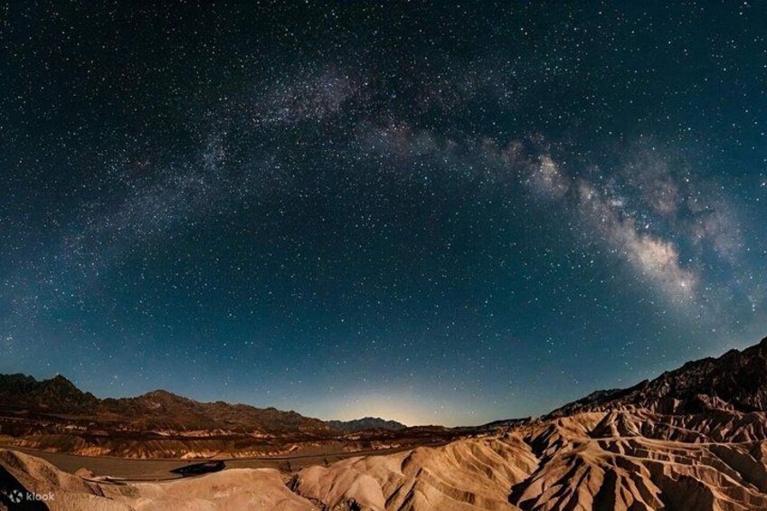 A starry night sky over a desert landscape with mountains in the foreground. 5