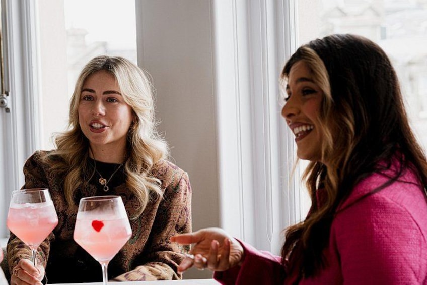 Two people sitting at a table with drinks, a window in the background. 2
