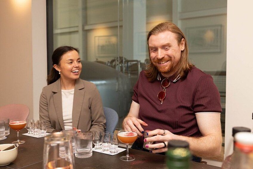 Two people sitting at a table with drinks and glasses. 2