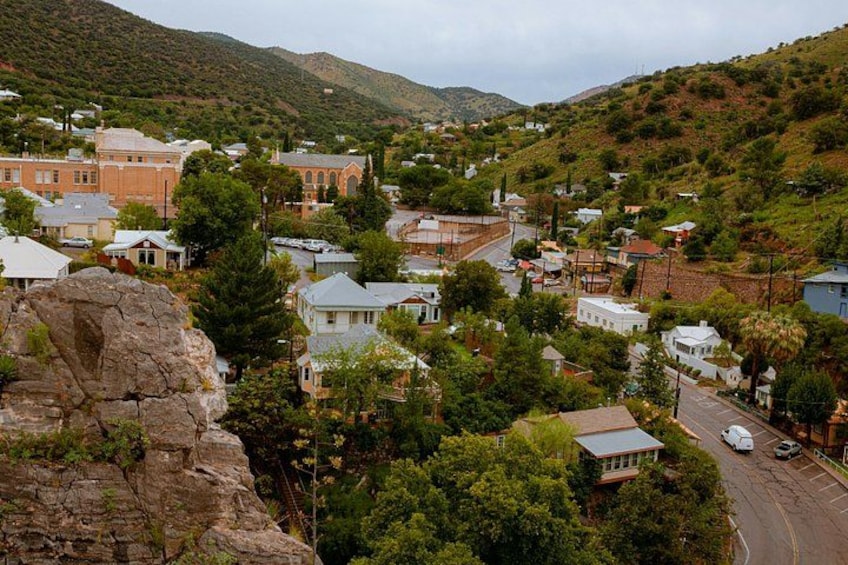 Un pueblo enclavado en un valle con edificios, una formación rocosa destacada y una carretera. 4