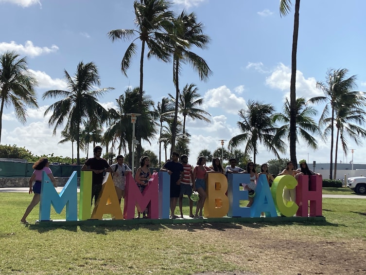 A group of people standing behind large colorful letters spelling 'MIAMI BEACH.' 4