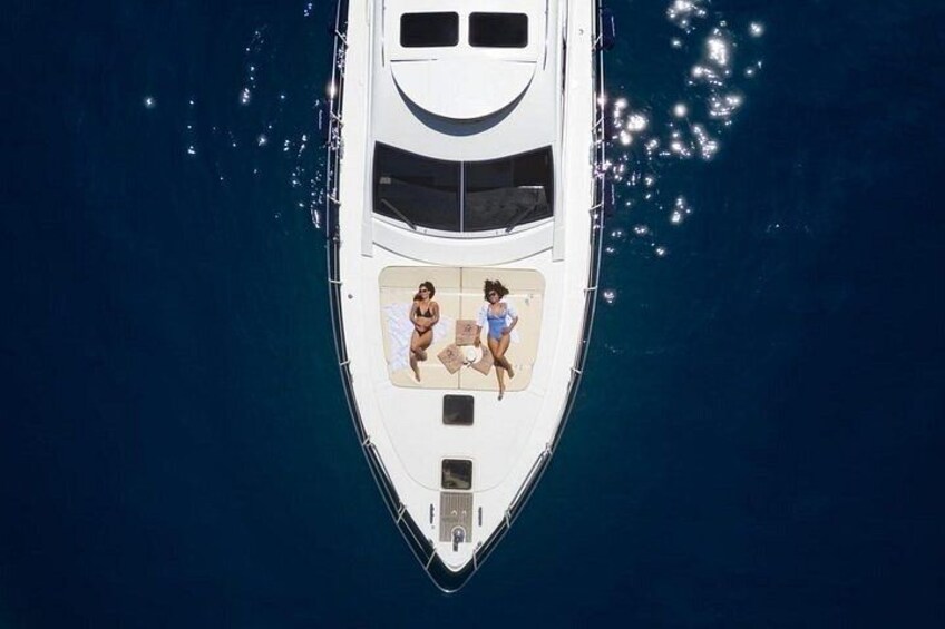 A white yacht with two people on deck, surrounded by deep blue water. 2
