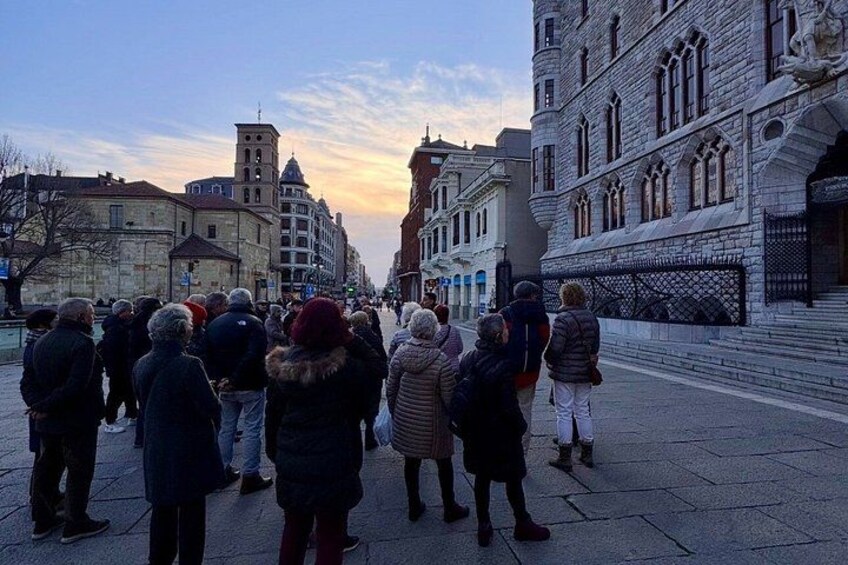 Eine Gruppe von Menschen steht auf einem Stadtplatz, im Hintergrund sind Gebäude und der Himmel ist klar. 4