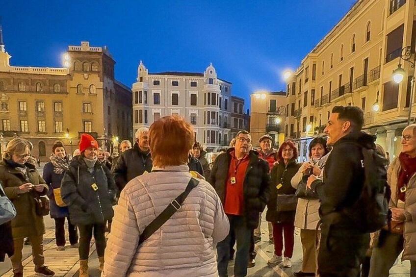 Eine Gruppe von Menschen steht nachts auf einem öffentlichen Platz. 3