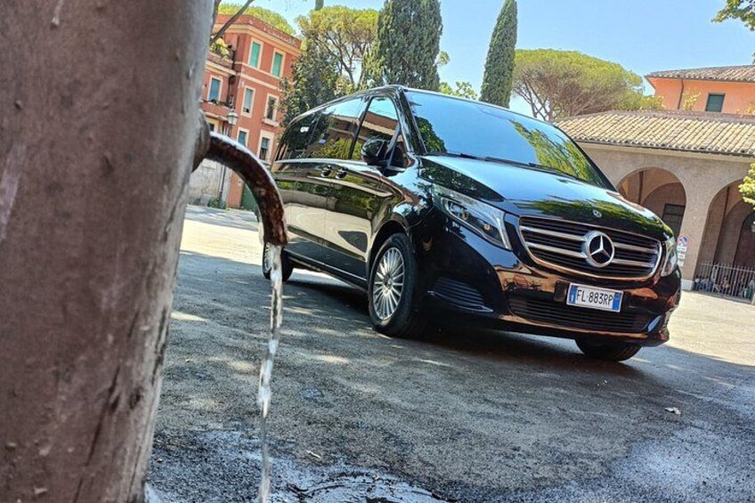 Una Mercedes-Benz nera parcheggiata su una strada, con un albero sullo sfondo. 1