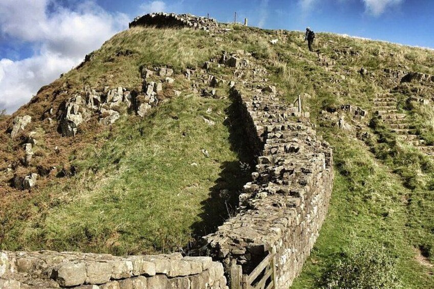 Un escalier en pierre menant au sommet d’une colline herbeuse, où se trouvent des ruines. 2