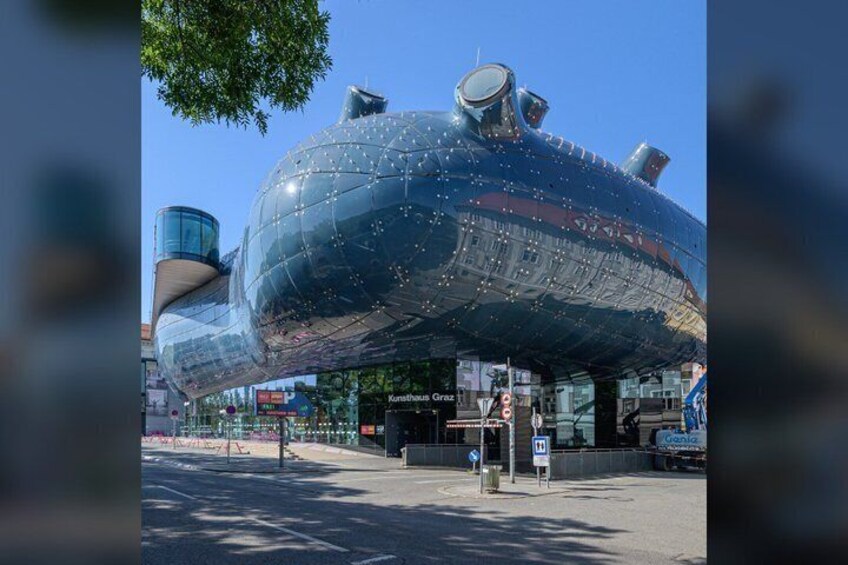 A large, spherical structure with a reflective surface, possibly a modern art installation, in an urban setting with a clear sky. 4
