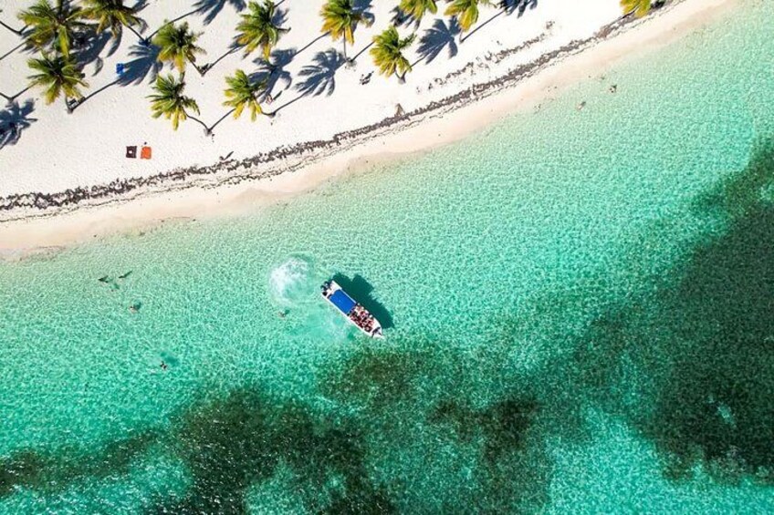 A boat on a turquoise beach with palm trees and a lifeguard tower. 5