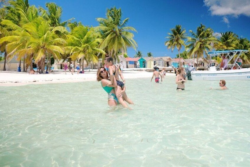 A beach with clear turquoise water, palm trees, and people swimming and playing. 2