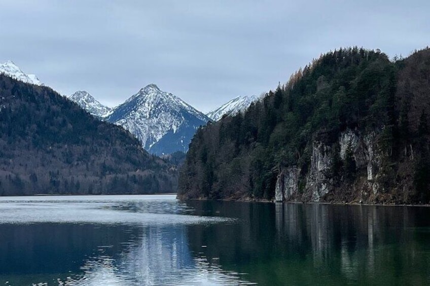 A calm lake surrounded by forested mountains with snow-capped peaks. 3