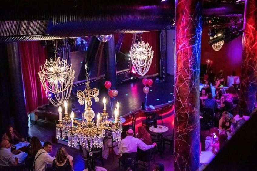 Un bar con candelabros, mesas y gente. 1