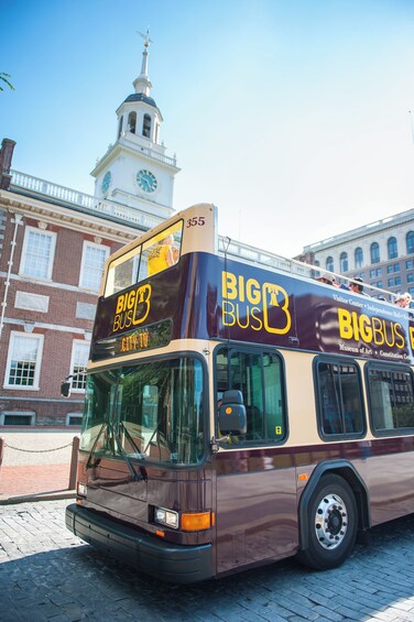 Un autobús de dos pisos con la marca 'BIG BUS', estacionado frente a un edificio histórico con una torre de reloj. 5