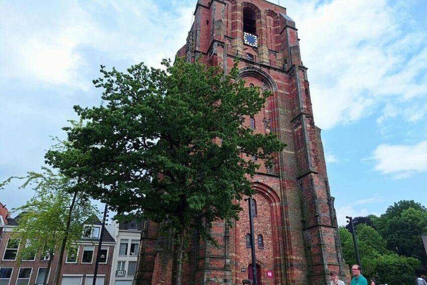 A tall brick church with a clock tower, surrounded by trees and buildings. 2