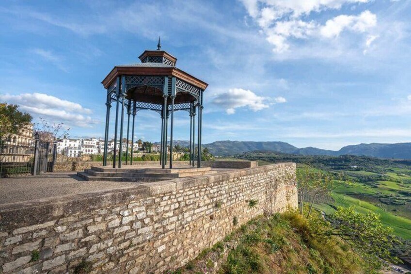 A stone wall, a gazebo, and a mountainous landscape. 3