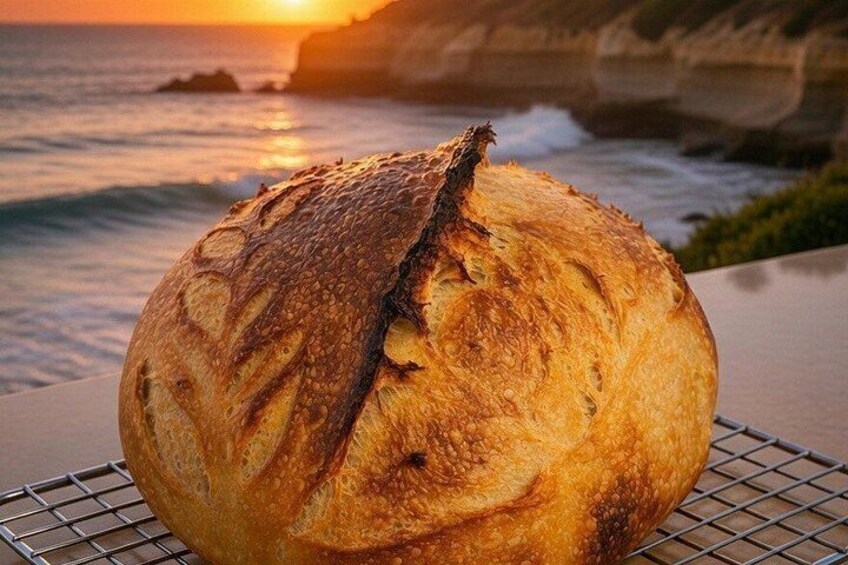 A loaf of bread with a crusty exterior on a cooling rack by the ocean at sunset. 5