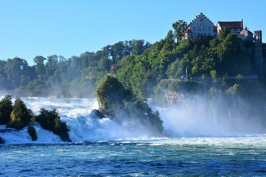 Un río con aguas turbulentas, un castillo en una colina y abundante vegetación. 2
