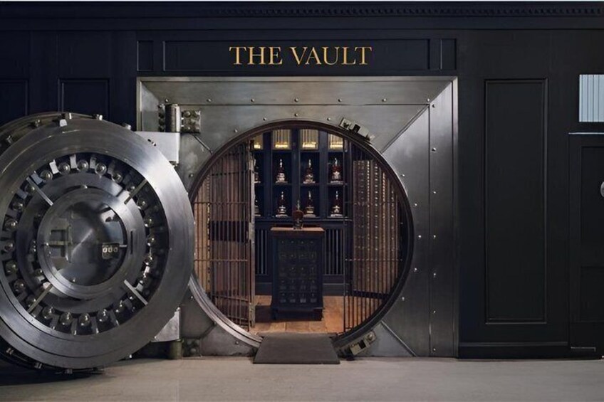 En stor pengeskabslåge med 'THE VAULT' skrevet over, et rundt syningsvindue og en udstillingsmontre indeni. 1